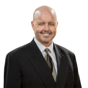 Chris Wiggins - WBG - 500x500 Chris Wiggins professional headshot wearing a dark suit, white dress shirt, and light-colored tie against a light gray background.