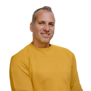 Doug Smithe - WBG - 500x500 Doug Smithe professional headshot wearing a mustard yellow crewneck sweater against a light gray background.