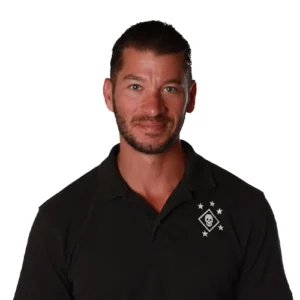 Marc Arrington professional headshot wearing a black polo shirt with an embroidered logo against a light gray background.