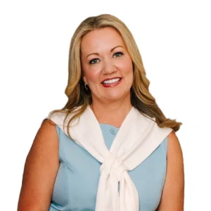 Phebe Ellis-Roach - WBG - 500x500 Phebe Ellis Roach professional headshot wearing a light blue sleeveless top with a white sweater draped over the shoulders against a light gray background.
