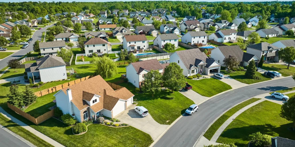 69cdb956-9e3b-3349-0b64-c207ca256094 Suburban residential community featuring detached homes, landscaped lawns, and a quiet neighborhood street.