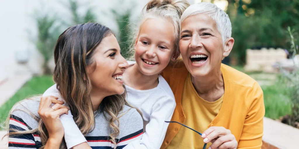 Multigenerational family enjoying time together outdoors, featuring an older adult, a child, and an adult in a garden.