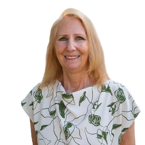 Diana professional outdoor headshot wearing a blue top and textured cardigan with greenery in the background.